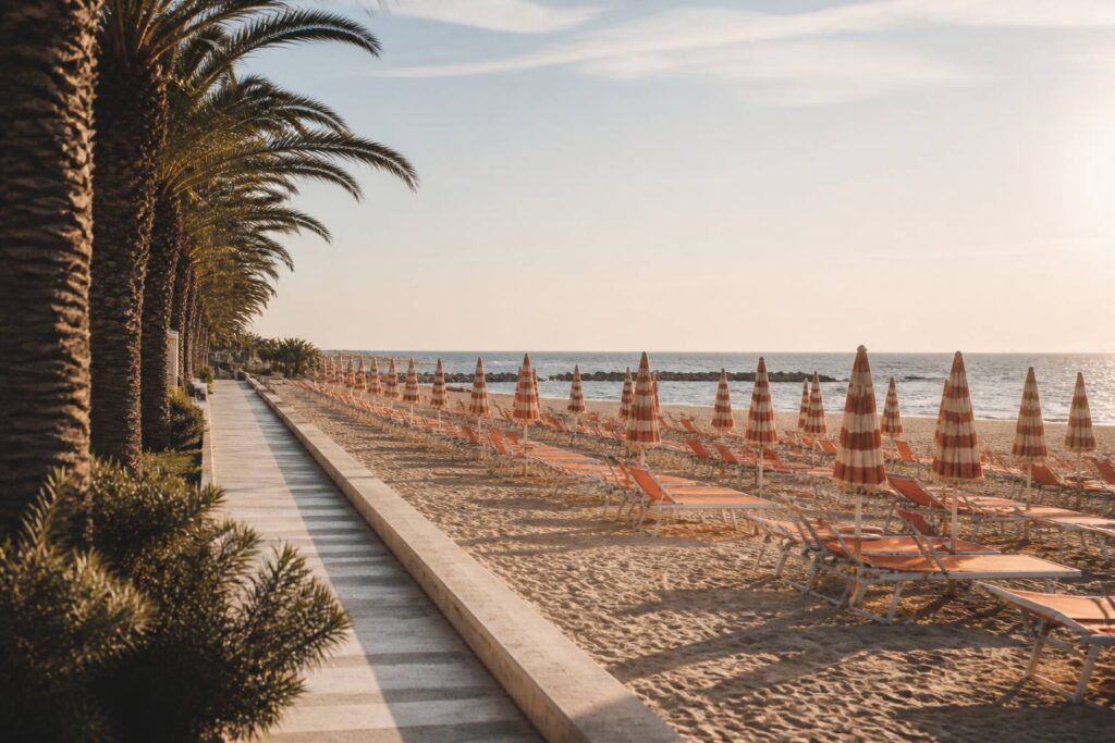 Plage de sable avec parasols, palmiers et mer adriatique